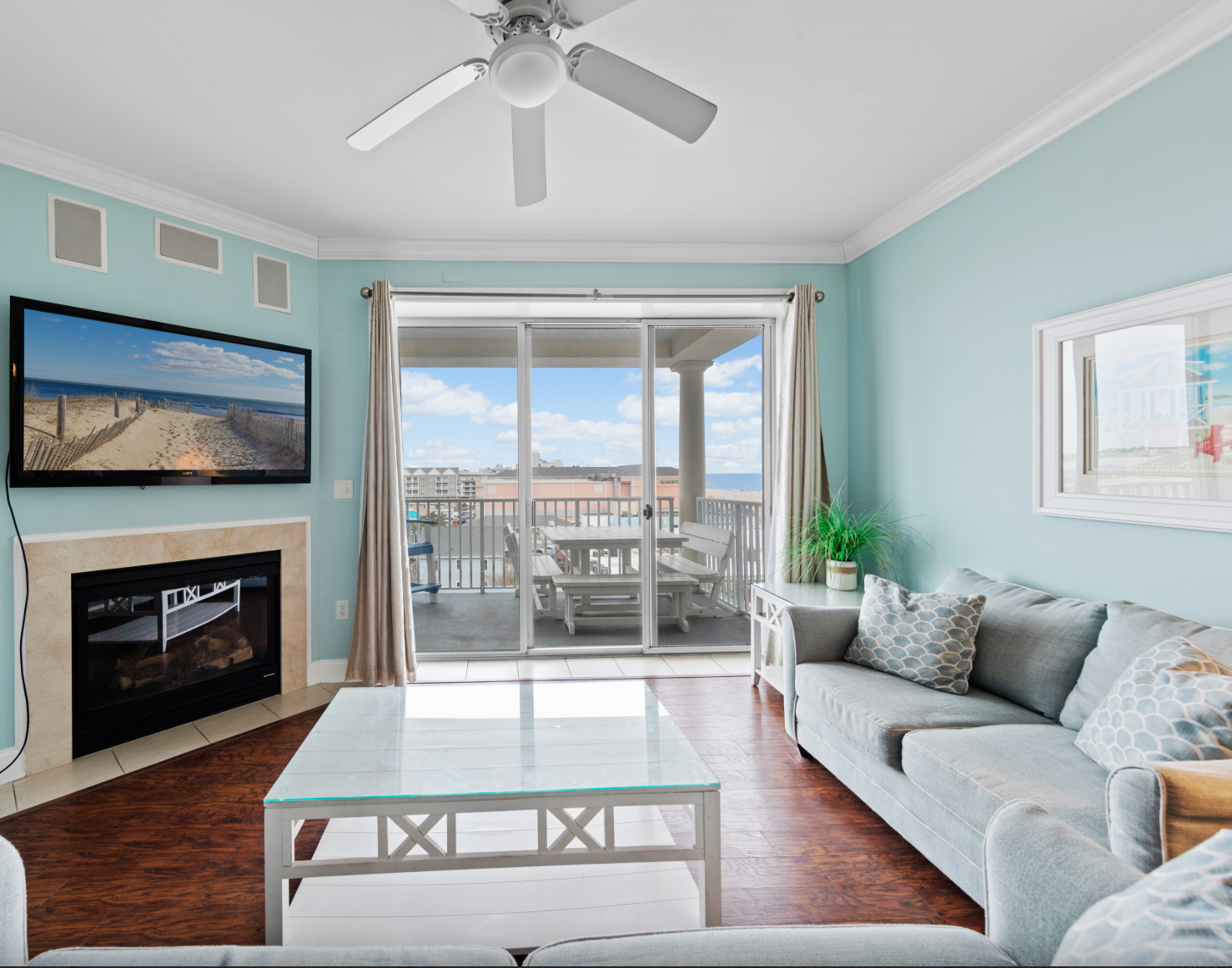 Den of a condo rental, with a television, fireplace, sofa, and balcony